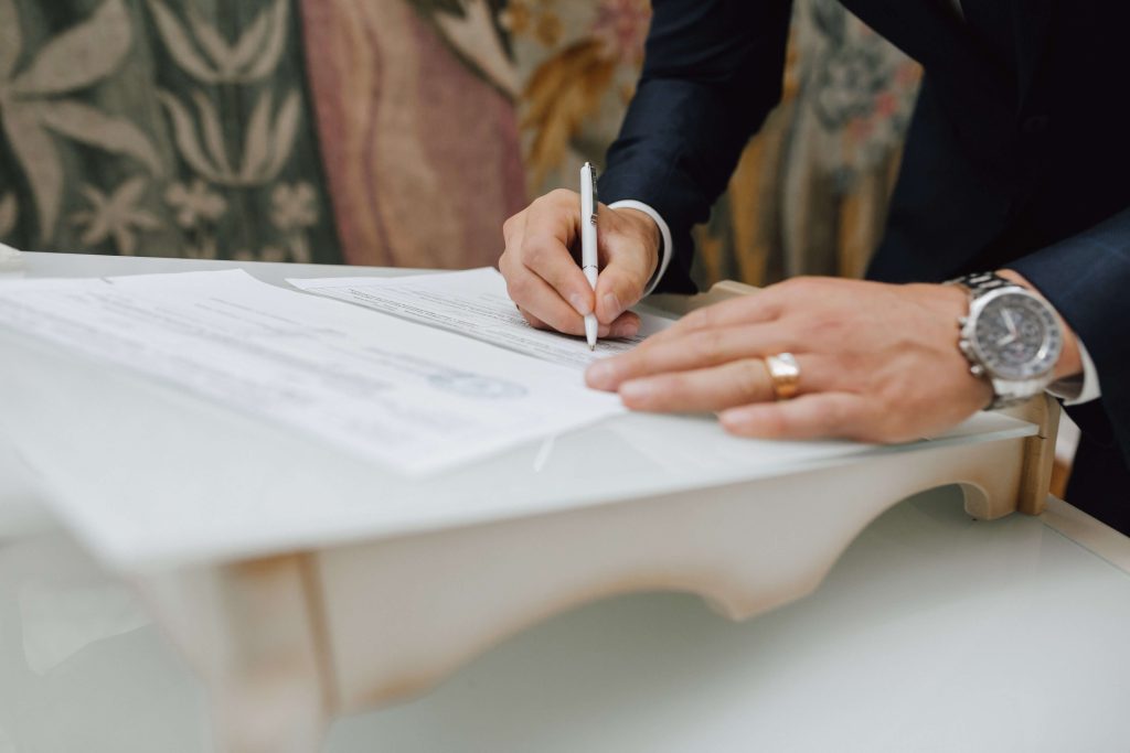 man signs document with a pen